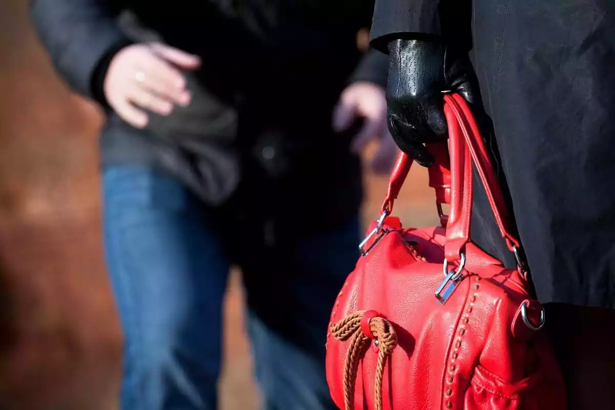 Un lladre intentant robar la bossa de mà d'una dona