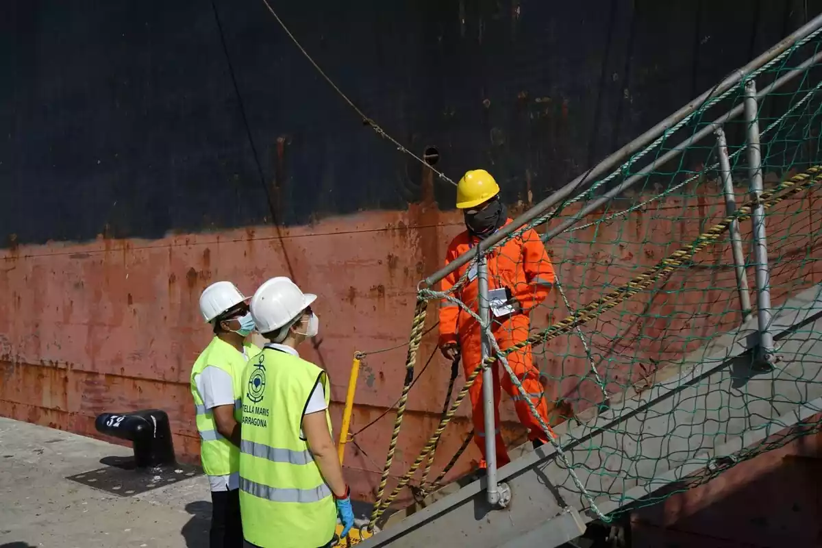 Image de dos voluntaris d'Stella Maris parlant amb el tripulant d'un vaixell al Port de Tarragona