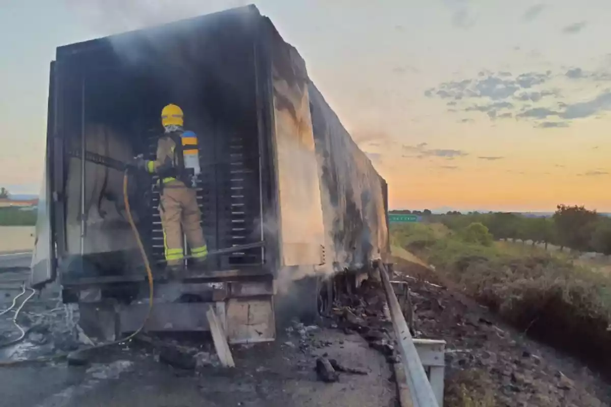 Imatge d'un bomber apagant les flames del camió incendiat
