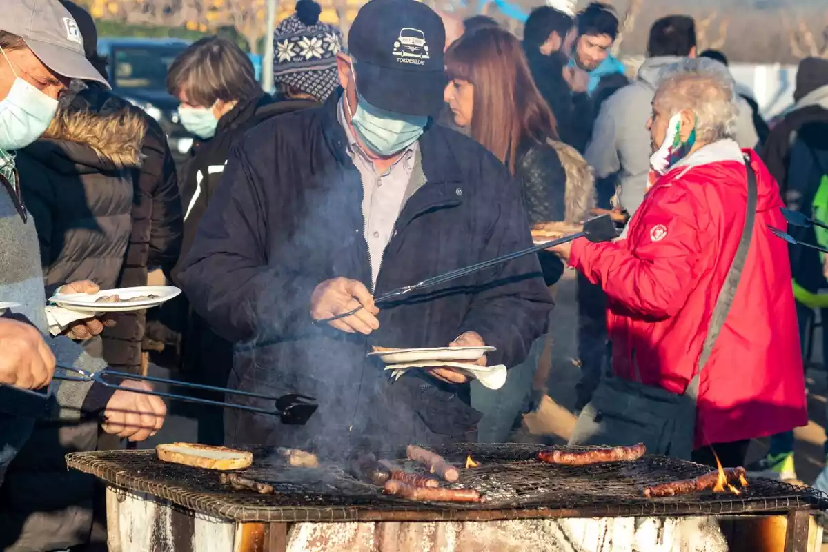 Imatge d'un home cuinant llonganissa i torrant pa a la Festa de l'Oli del Morell