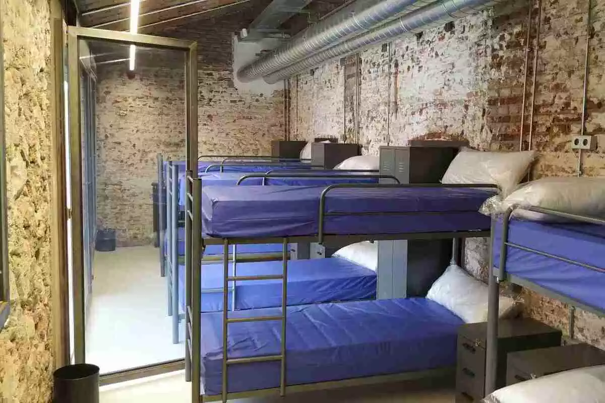 Una habitació amb quatre lliteres de dos llits i una porta exterior