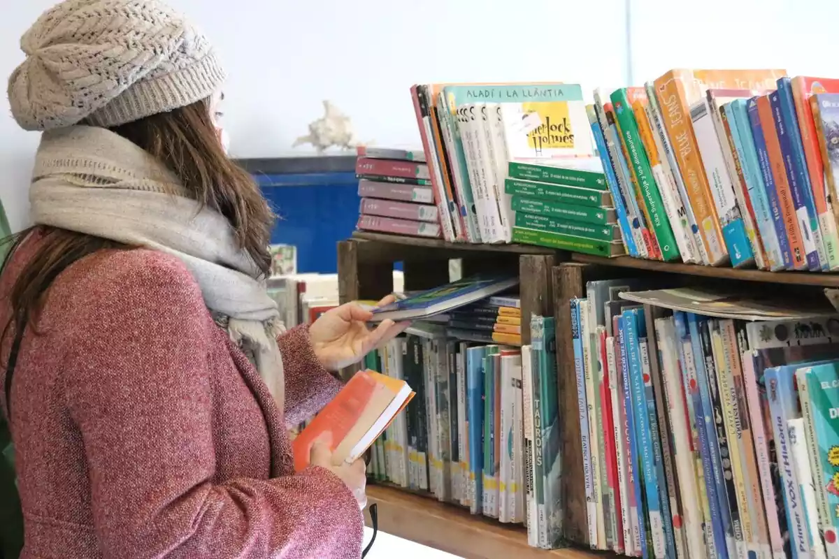 Una noia mirant llibres en una llibreria.