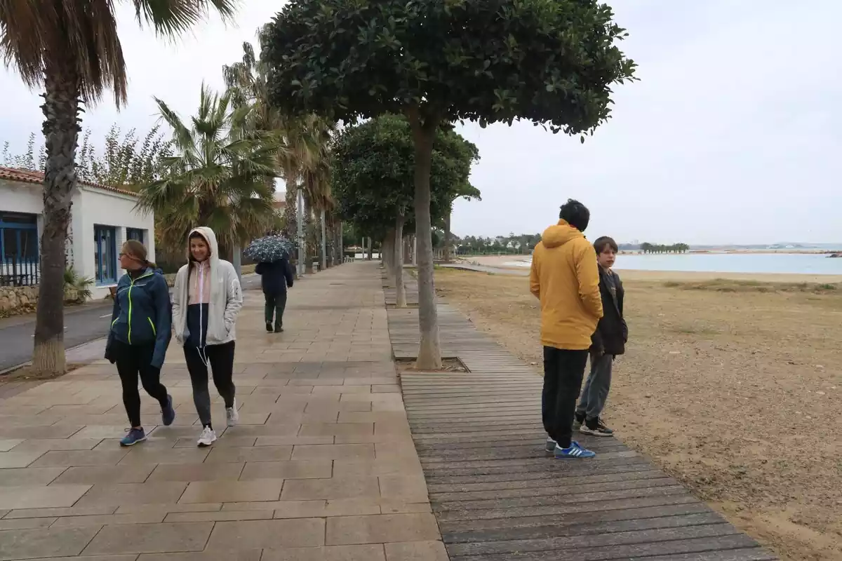 Diverses persones passegen amb paraigües pel passeig marítim de Cambrils, l'últim dia del pont de desembre