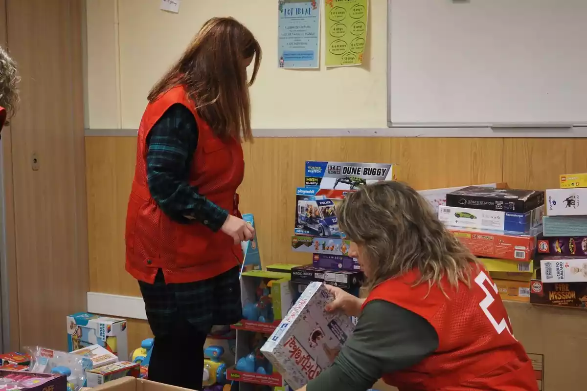 Imatge de dues voluntàries de la Creu Roja preparant els jocs i joguines recollits durant la campanya