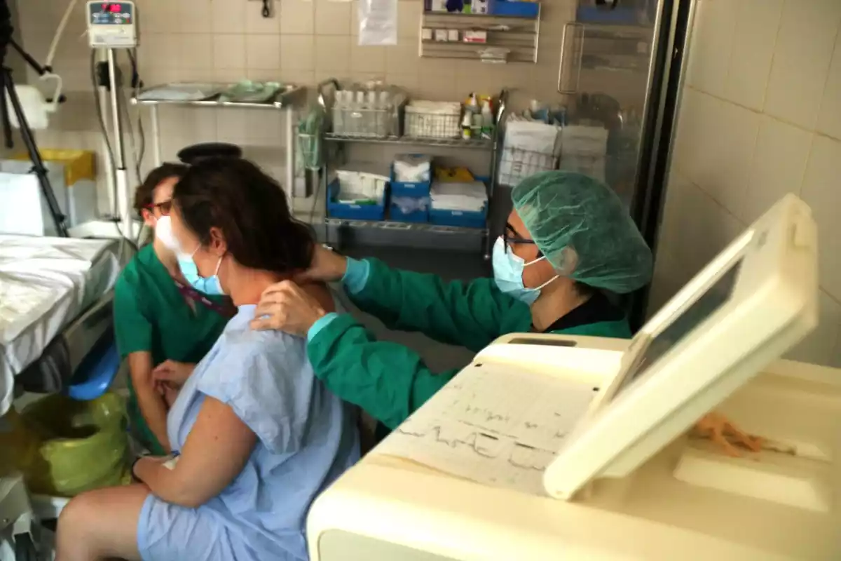 Una llevadora acompanyant en el part a una dona embarassada i la seva parella