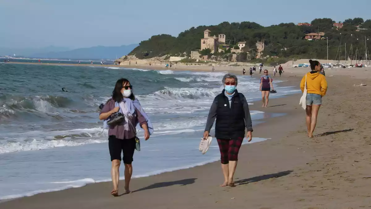 Dues dones amb mascareta caminant per la platja d'Altafulla en el primer dia permès per sortir a practicar esport