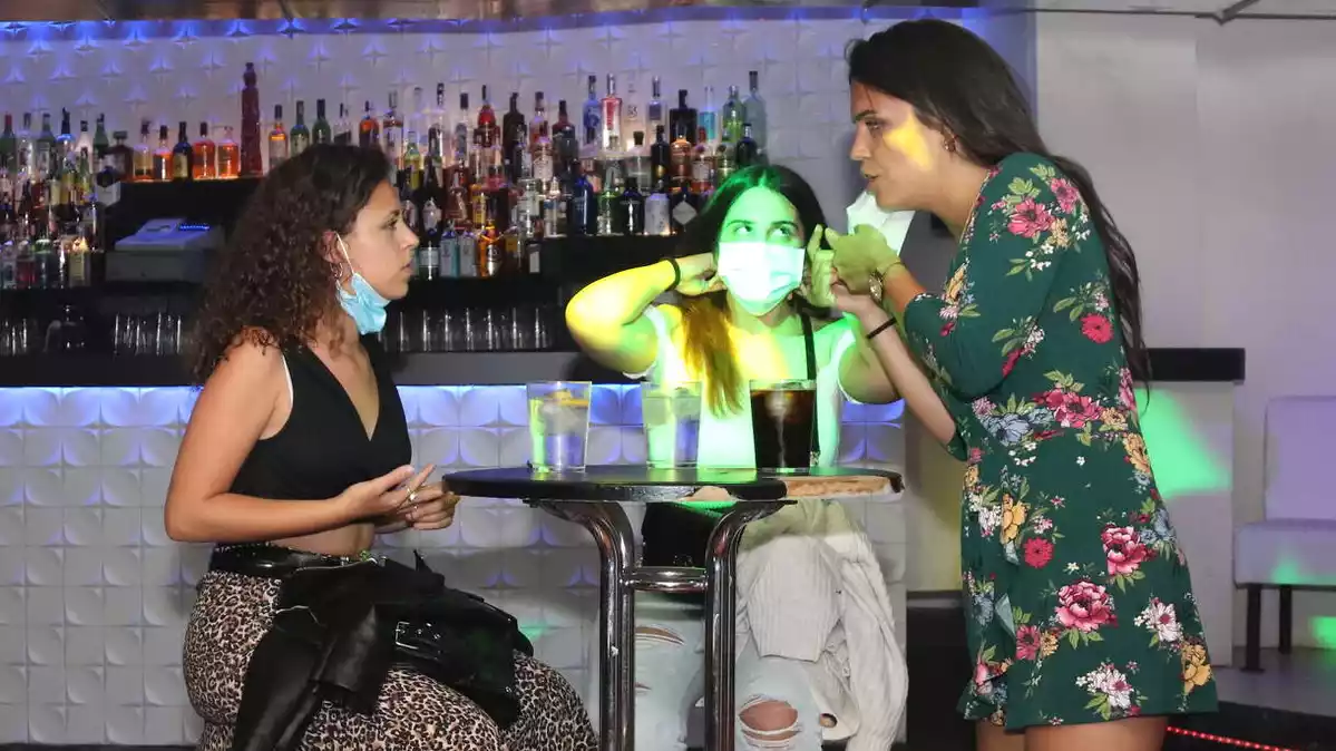 Tres clientes de la discoteca Totem, fent una copa en una de les taules que s'han col·locat