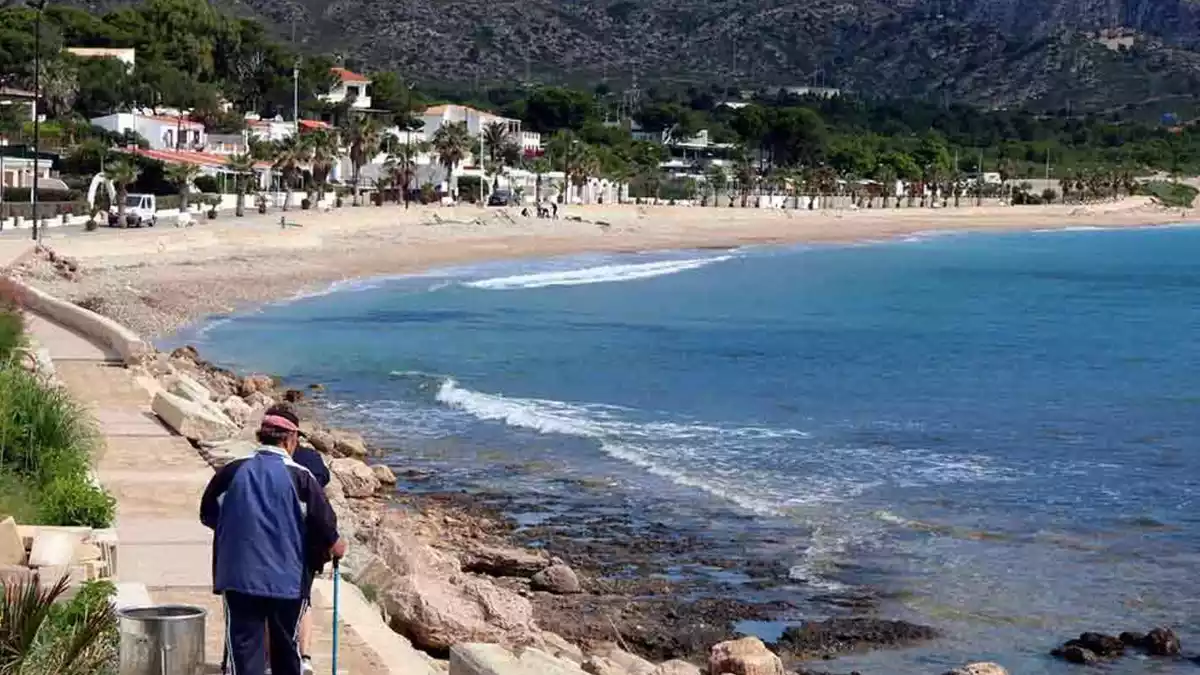 Dues persones que passegen en direcció a la platja de l'Almadrava, al municipi de Vandellòs i l'Hospitalet de l'Infant.