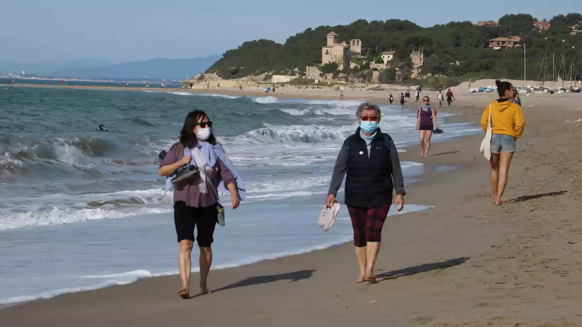 Dues dones amb mascareta caminant per la platja d'Altafulla en el primer dia permès per sortir a practicar esport