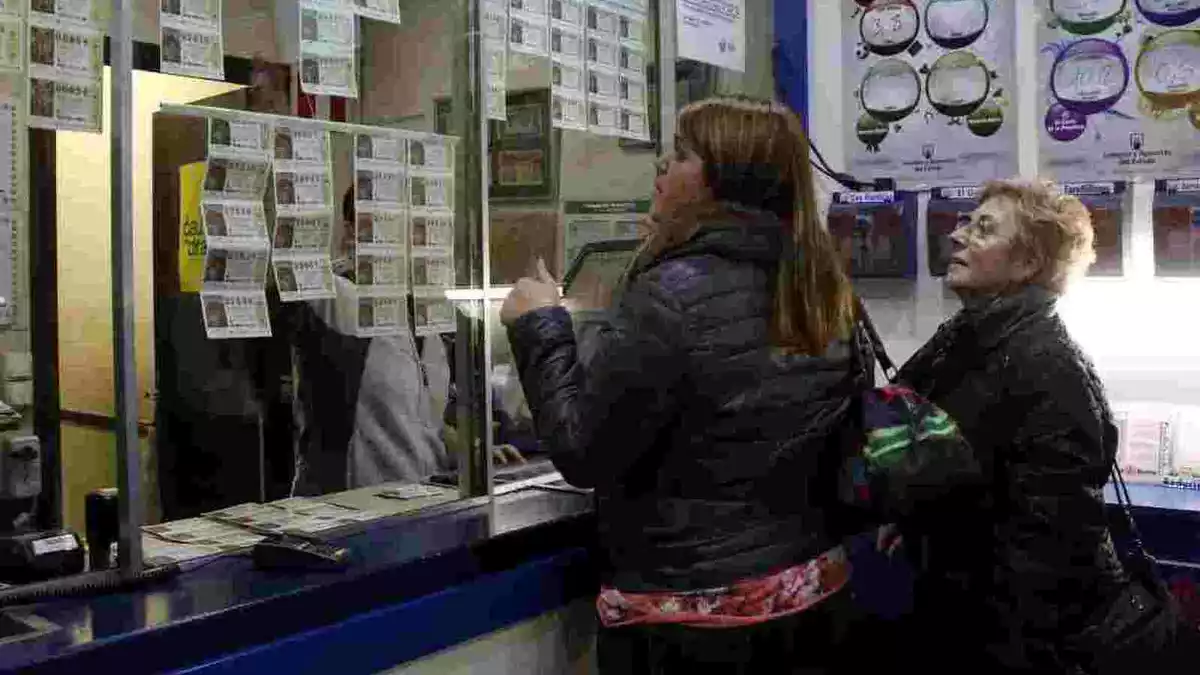 Dues dones escullen el número de loteria de la Grossa de Nadal en una administració de lotería