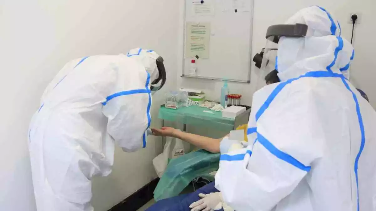 Professionals del CAP Manso, amb equip de protecció individual (EPI), en el moment d'extreure una mostra de sang a un pacient