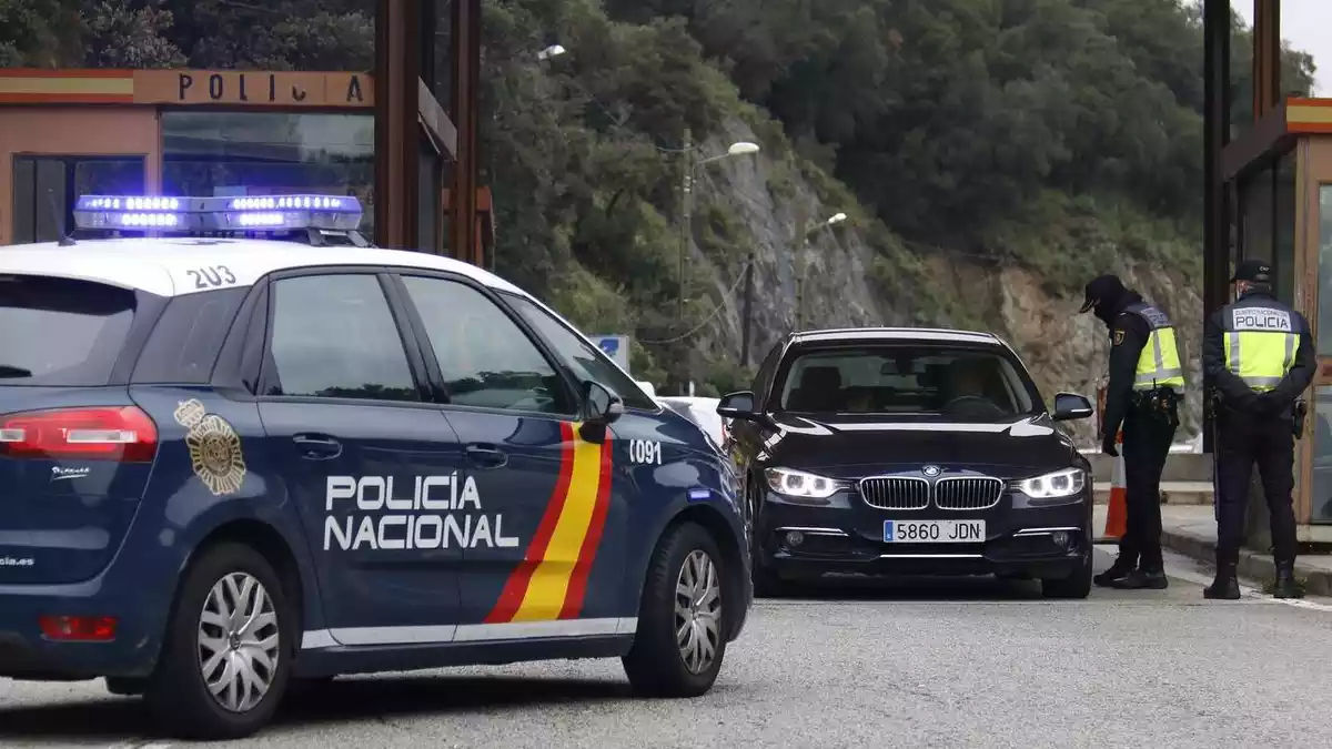 Dos agents de la Policia Nacional fent un control en un turisme espanyol que vol creuar la frontera al Pertús el 17 de març de 2020.