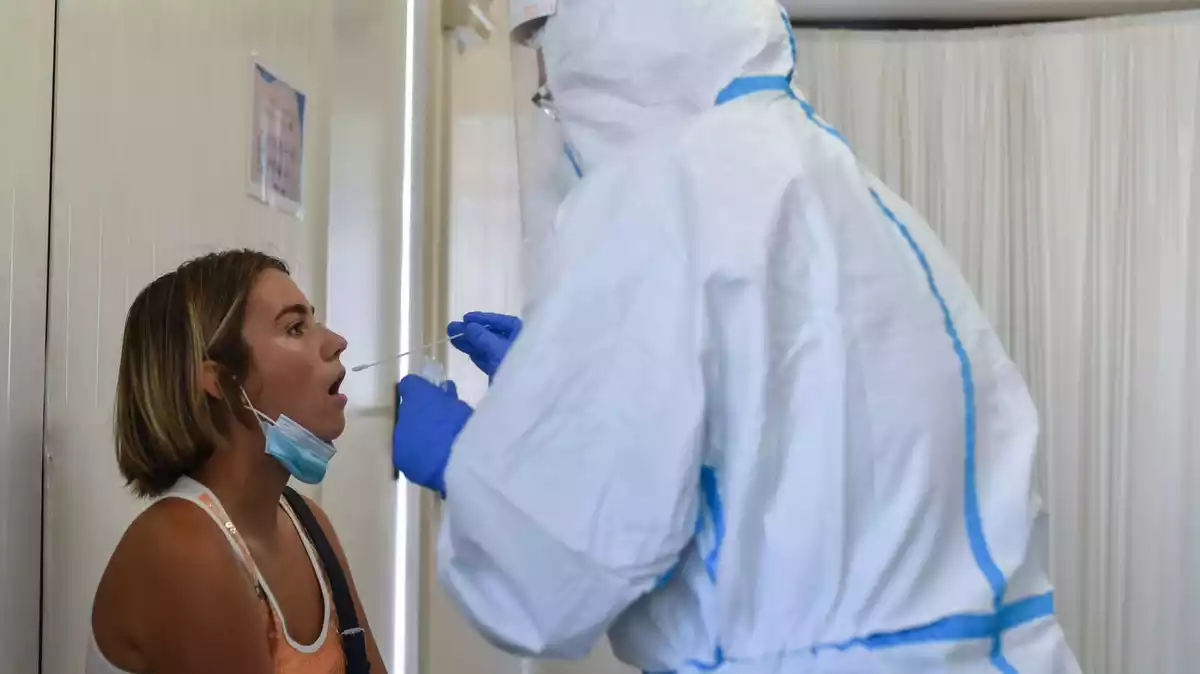 Una noia amb la boca oberta mentre un sanitari li pren mostres per fer la PCR