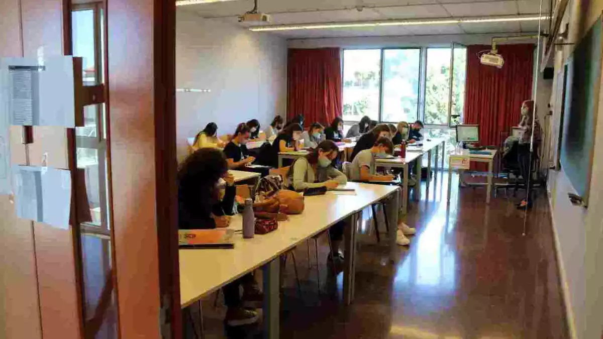 Pla obert d'una aula de la URV, vista des de fora, amb alumnes fent classe amb mascareta en el primer dia del curs 2020-2021