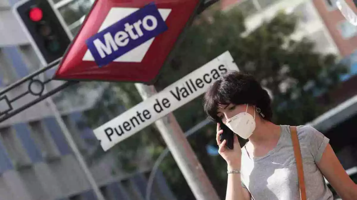 Una dona, parlant per telèfon, passa per davant de la parada de metro del districte madrileny de Puente de Vallecas