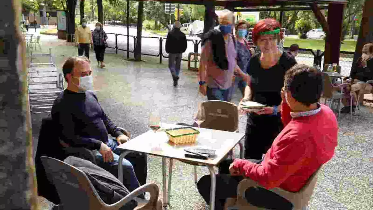 Imatge d'una terrassa de bar a la ciutat de Saragossa, amb una cambrera atenent dos clients