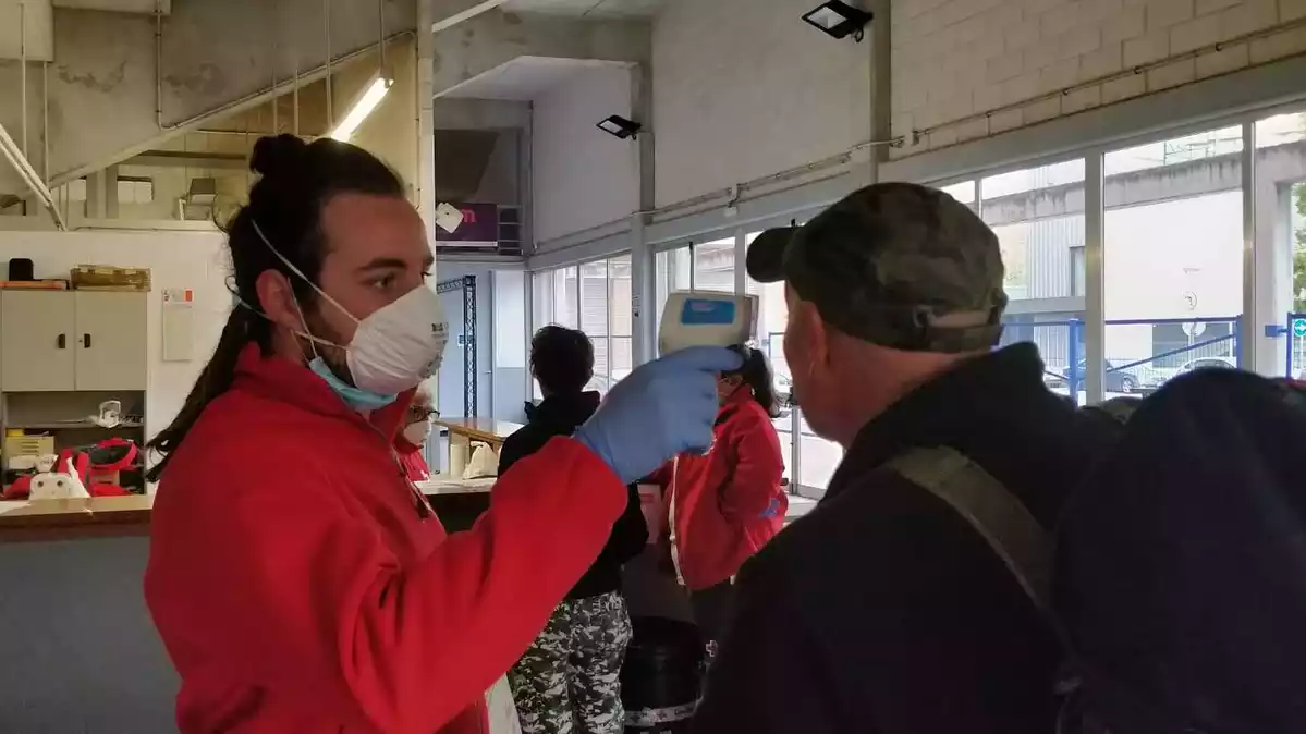 Un dels voluntaris de Creu Roja mesura la temperatura a una de les persones sense sostre