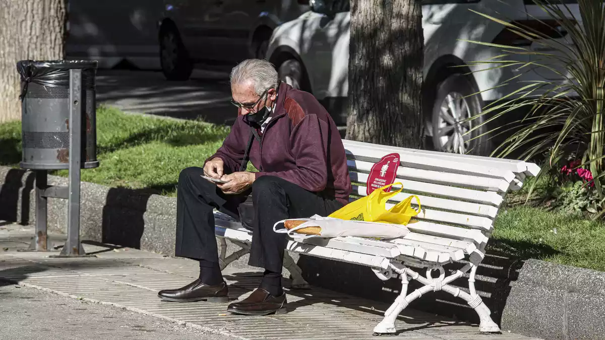 Imatge d'un senyor gran assegut en un banc de la Rambla Nova