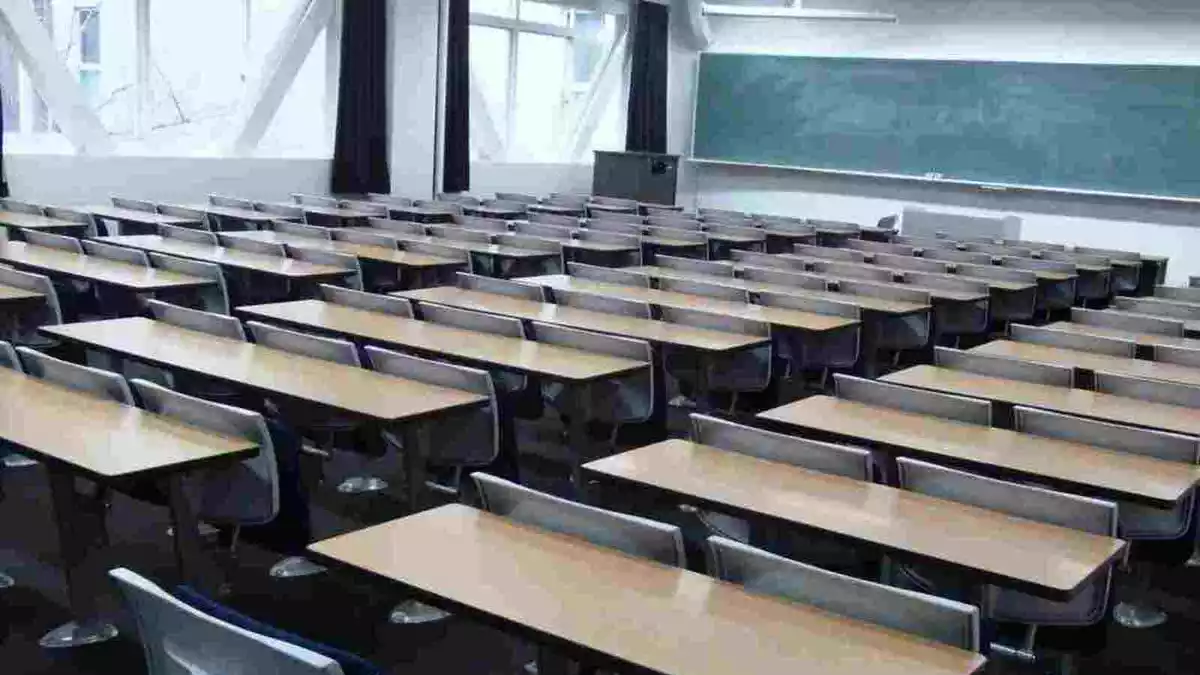 L'interior d'una aula amb taules, cadires i una pissarra