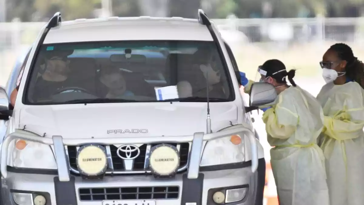 Sanitaris australians fan una prova PCR a una família en cotxe, a la ciutat d'Austràlia