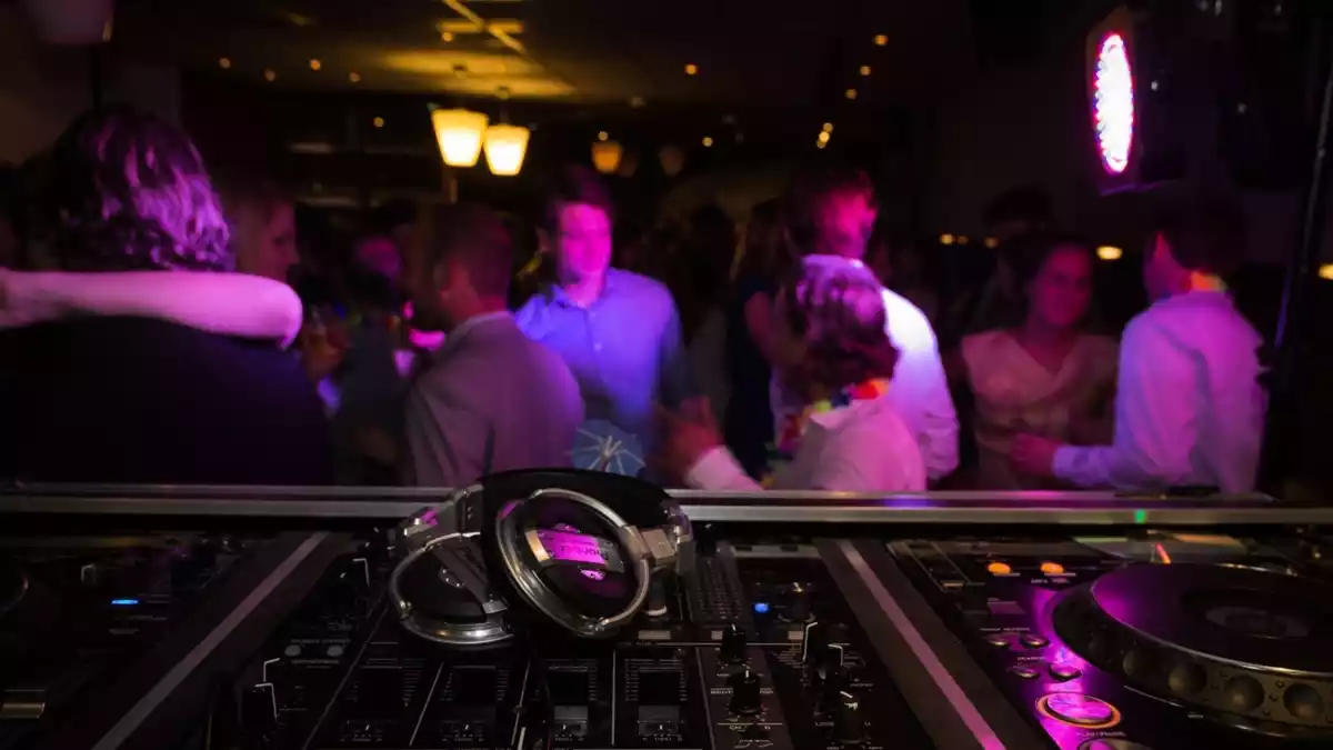 Diverses persones en una discoteca passant-ho bé i uns auriculars en primer pla