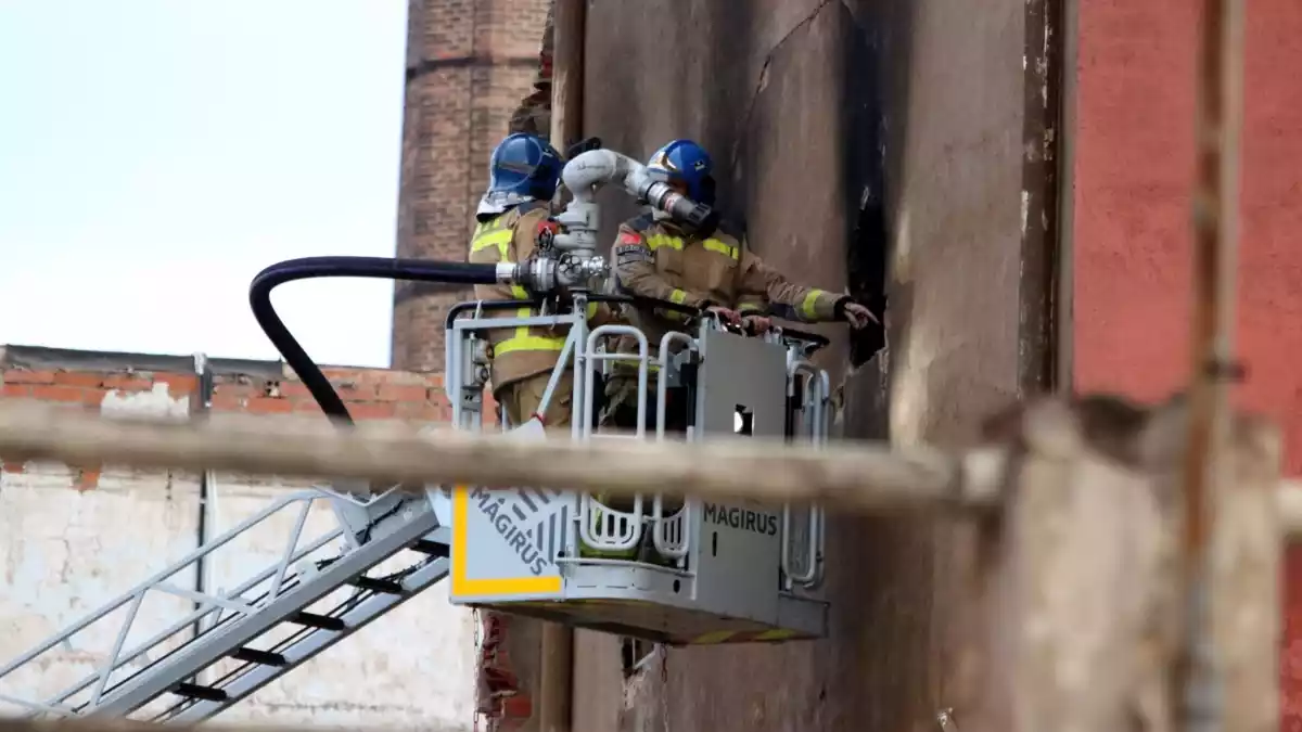 Dos bombers de la Generalitat estudiant la solidesa de la nau okupada i incendiada a Badalona