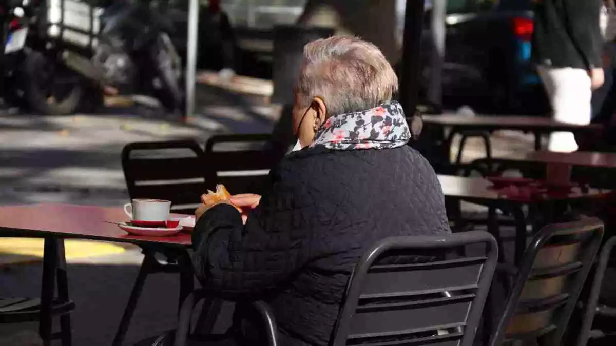 Una dona prenent un cafè asseguda en la terrassa d'un bar