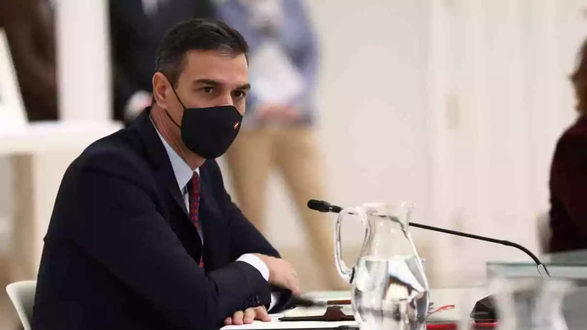 El president Pedro Sánchez amb mascareta i un micròfon davant, mirant al costat dret