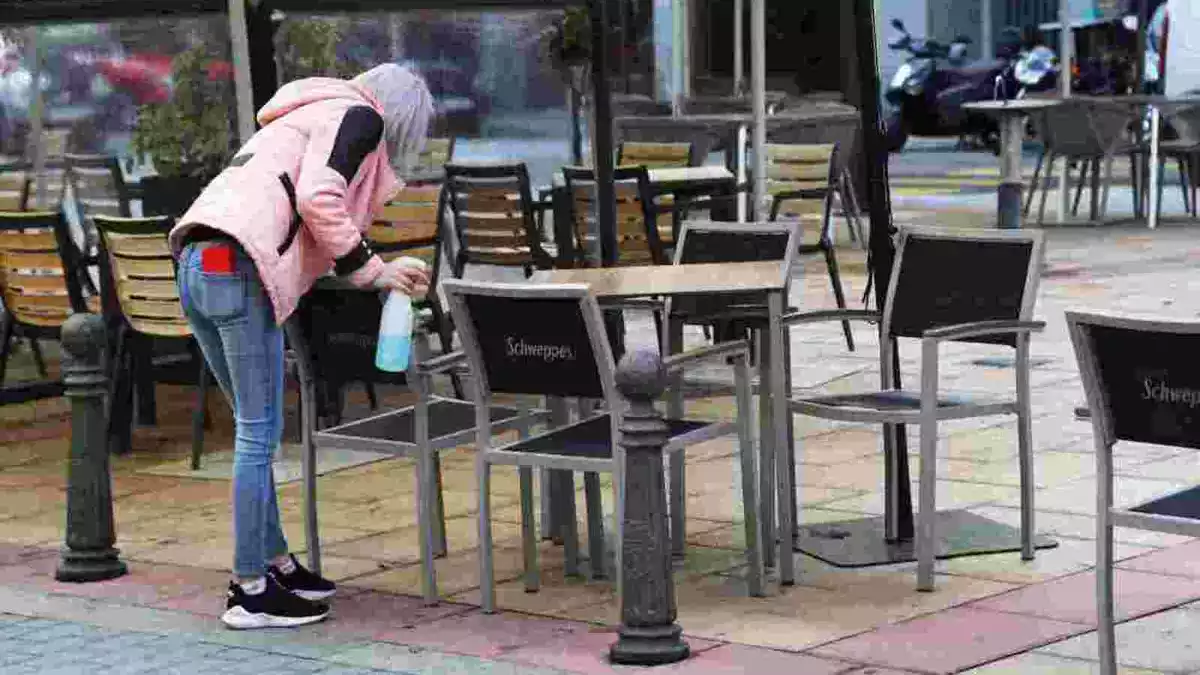 Una dona netejant una taula a la terrassa d'un local de la ciutat de Lleó