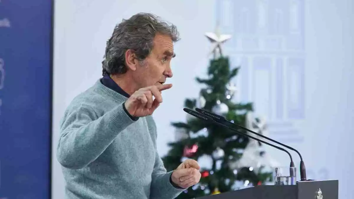 Fernando Simón amb el dit aixecat i un arbre de Nadal darrere en roda de premsa