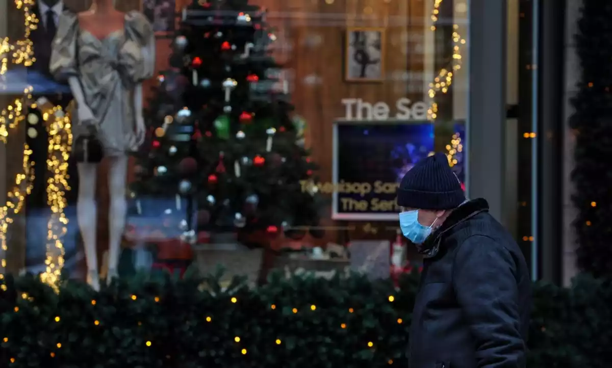 Un home amb mascareta passant per davant d'un arbre de Nadal i decoració diversa