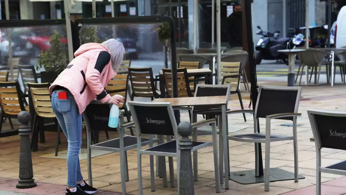 Una dona netejant una taula a la terrassa d'un local de la ciutat de Lleó