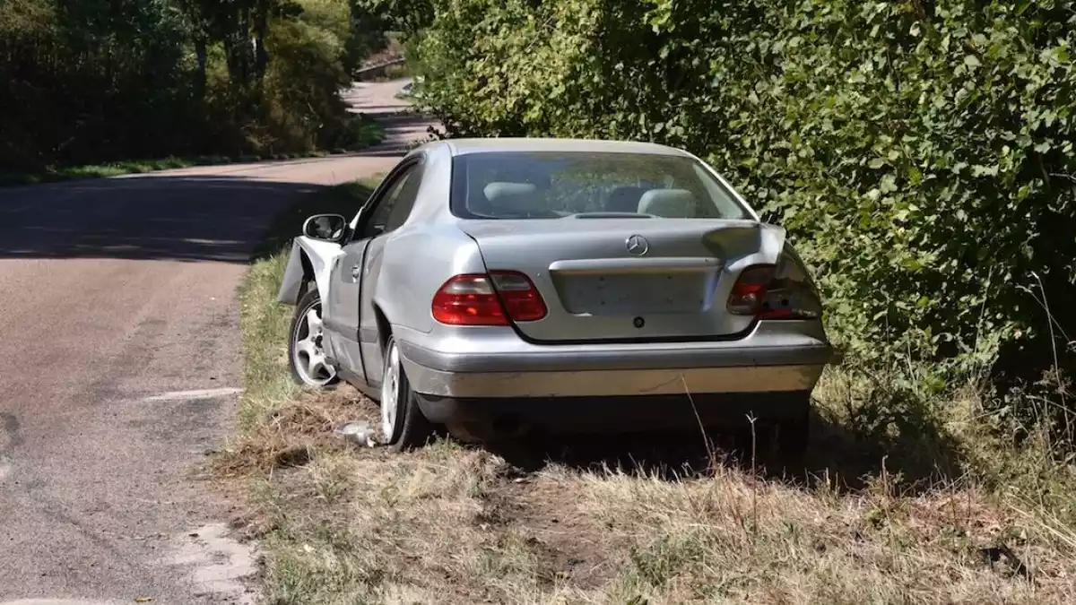 Imatge d'un cotxe abandonat a la vora d'un camí rural.