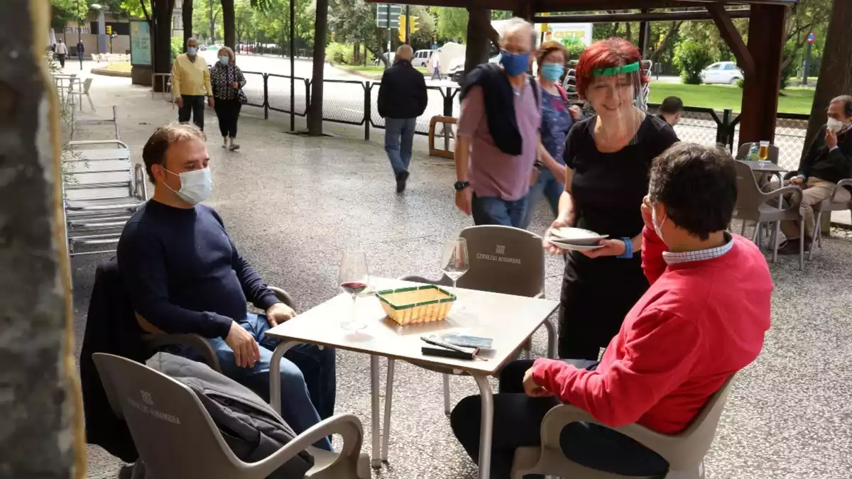 Imatge d'una terrassa de bar a la ciutat de Saragossa, amb una cambrera atenent dos clients