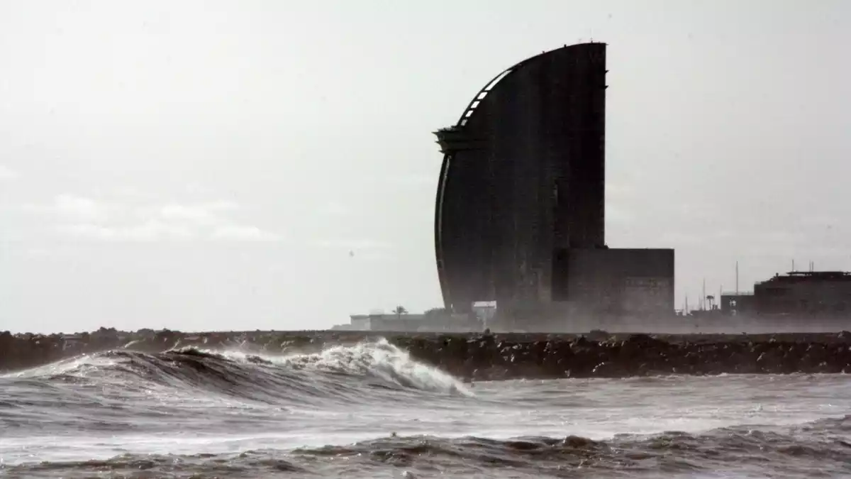 Primer pla de les onades a la platja de la Barceloneta amb l'Hotel Vela al darrera