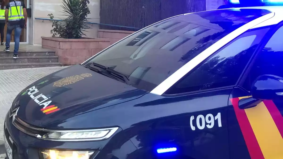 Primer pla d'un vehicle de la Policia Nacional mentre diversos agents entren en un edifici