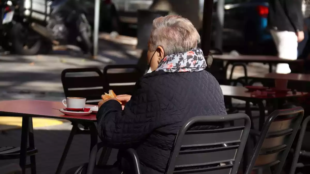 Una dona prenent un cafè asseguda en la terrassa d'un bar