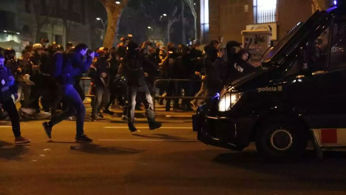 Manifestants davant d'una furgoneta dels Mossos d'Esquadra durant els aldarulls a Barcelona