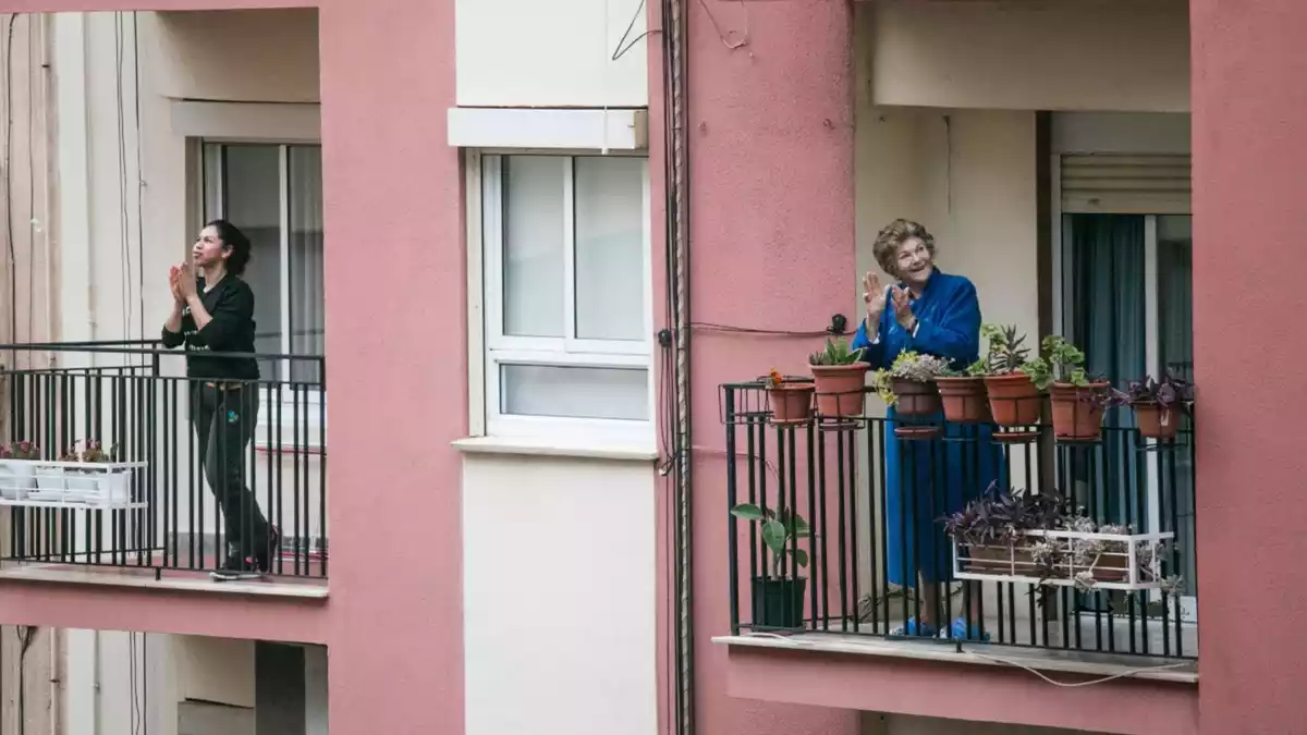 Dues dones aplaudint des dels balcons de casa seva