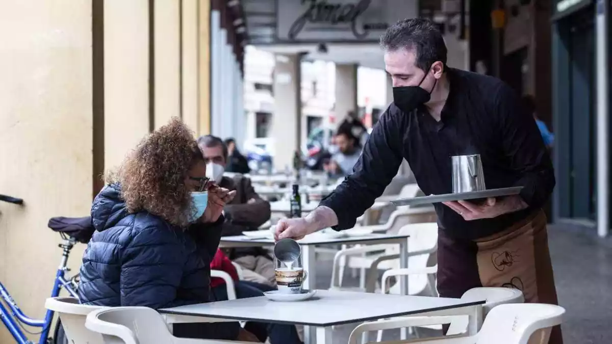 Imatge d'un cambrer servint un cafè a una clienta en una terrassa