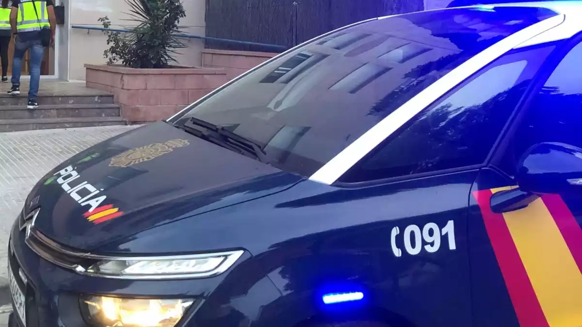 Primer pla d'un vehicle de la Policia Nacional mentre diversos agents entren en un edifici