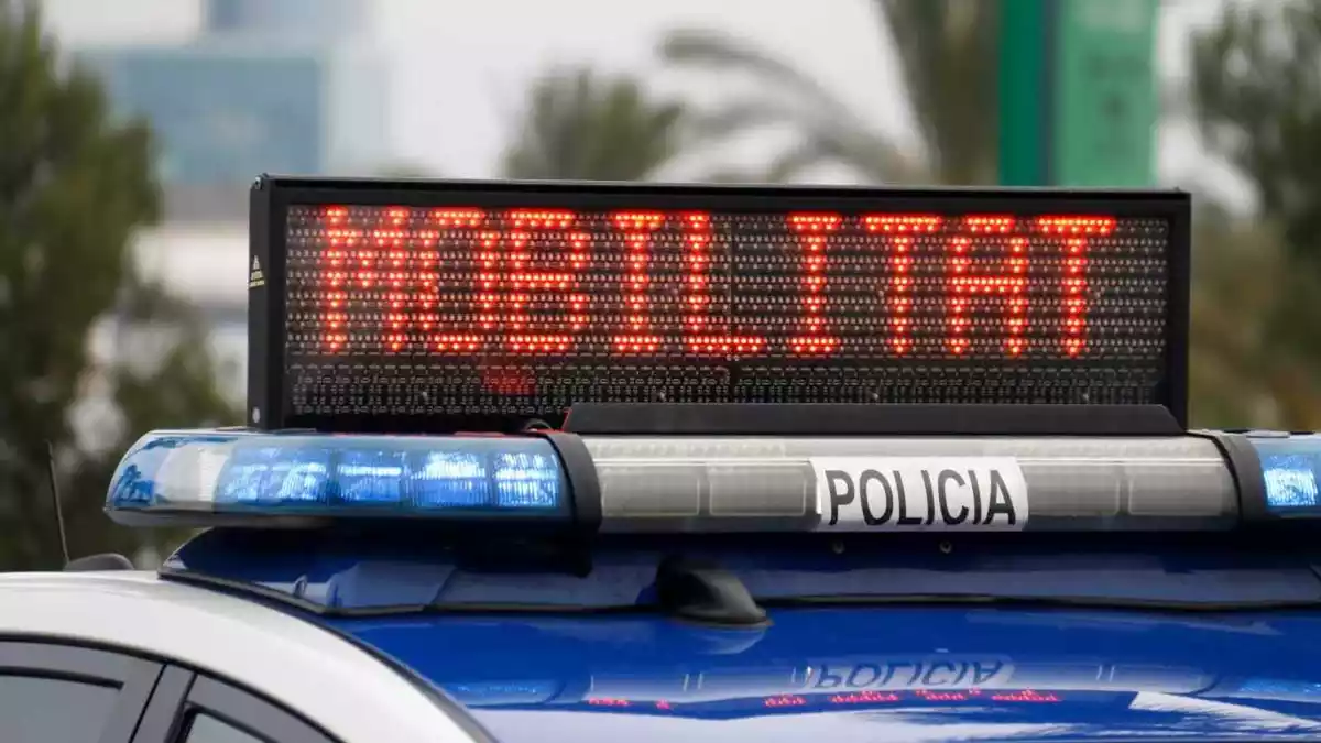 Un vehicle de policia amb un avís sobre la mobilitat restringida a Catalunya