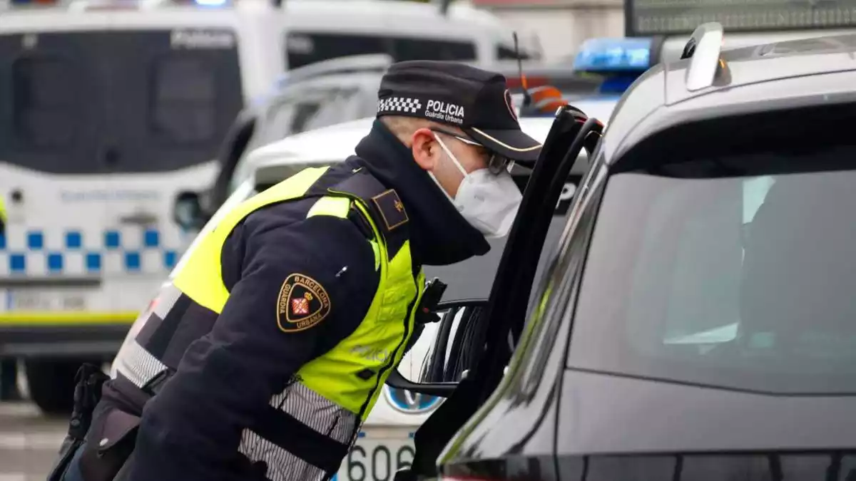 Un agent de la Guàrdia Urbana parla amb el conductor d'un vehicle en un control de mobilitat a la Ronda Litoral de Barcelona