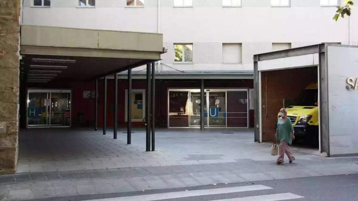 Pla obert on es veu una de les entrades del Sant Hospital de la Seu d'Urgell i una persona passant pel davant amb mascareta