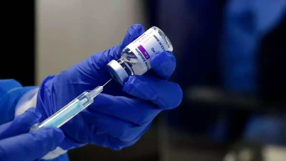 Una persona preparant una de les dosis de la vacuna d'AstraZeneca amb un vial a les mans