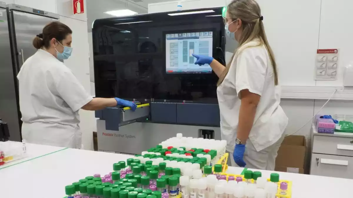 Dues professionals sanitàries amb unes proves PCR davant en un laboratori