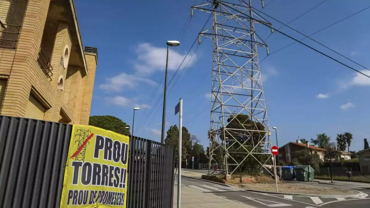 Una pancarta contra les torres elèctriques en una tanca just davant d'una d'aquestes instal·lacions a la urbanització el Pinar