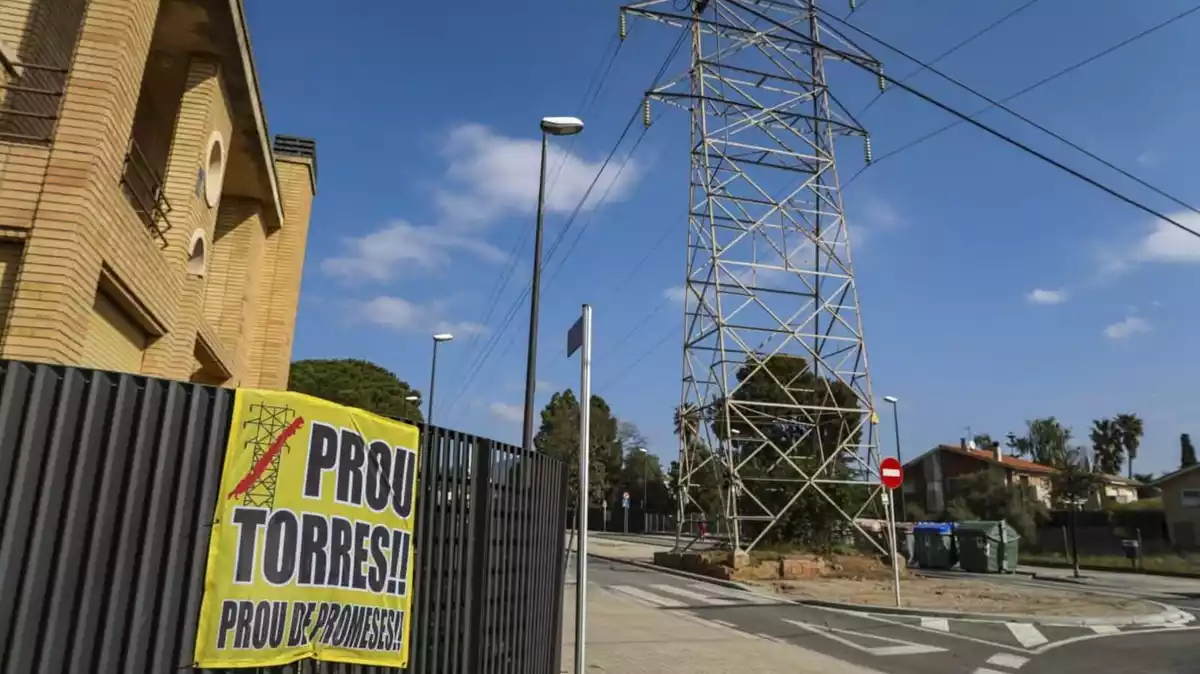 Una pancarta contra les torres elèctriques en una tanca just davant d'una d'aquestes instal·lacions a la urbanització el Pinar