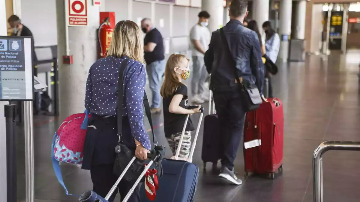 Tres persones amb maletes de viatge a la terminal de l'aeroport de Reus
