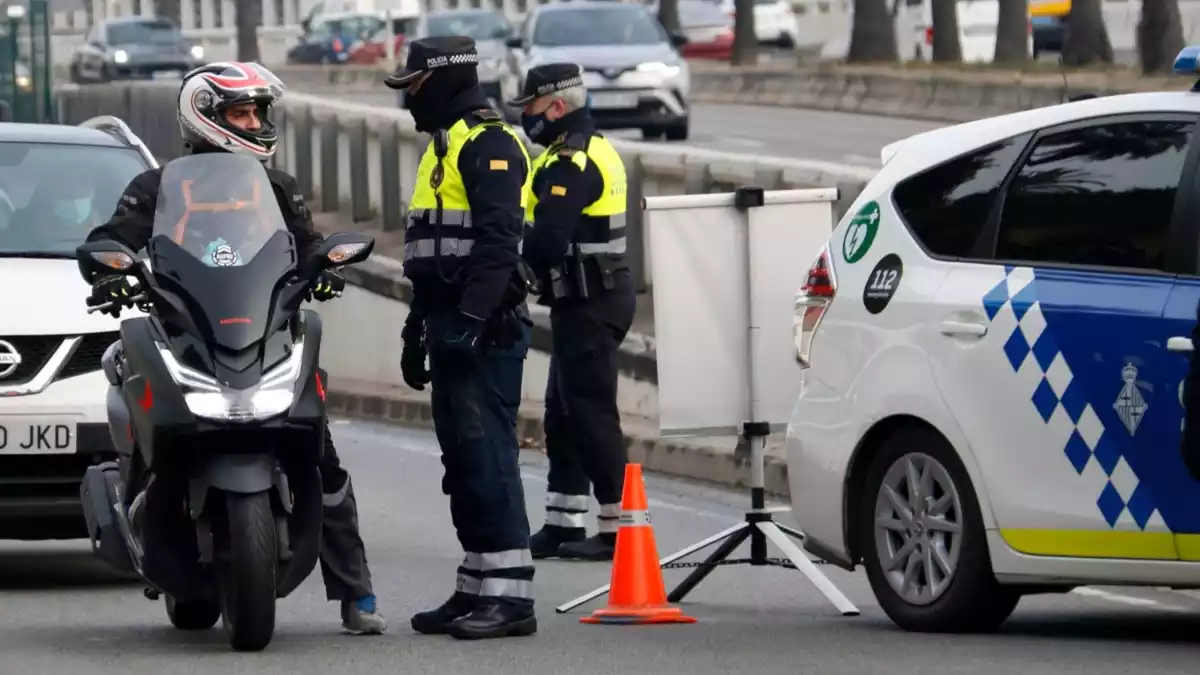 Dos agents de la Guàrdia Urbana de Barcelona parlant amb un motorista en un control policial